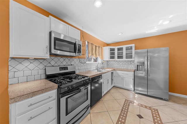 kitchen featuring backsplash, tile countertops, light tile patterned floors, stainless steel appliances, and a sink