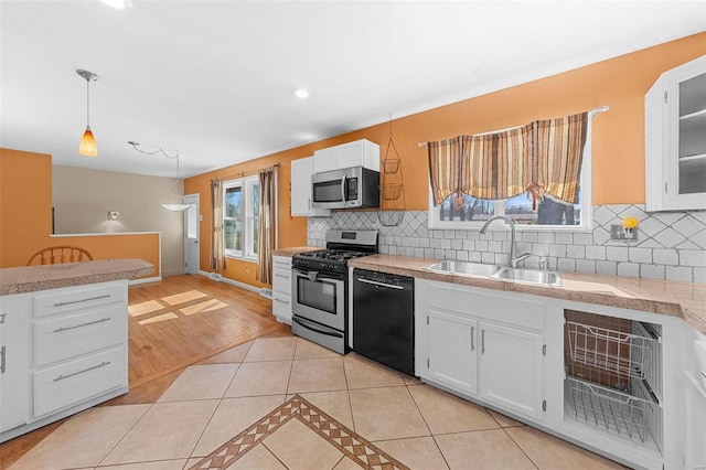 kitchen with pendant lighting, light tile patterned floors, stainless steel appliances, white cabinetry, and a sink