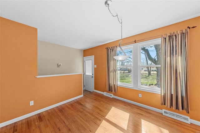 unfurnished dining area with wood finished floors, visible vents, and baseboards