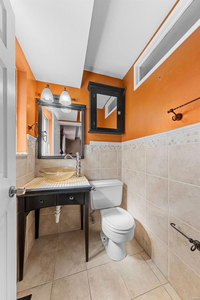 bathroom featuring a sink, toilet, tile walls, and tile patterned floors