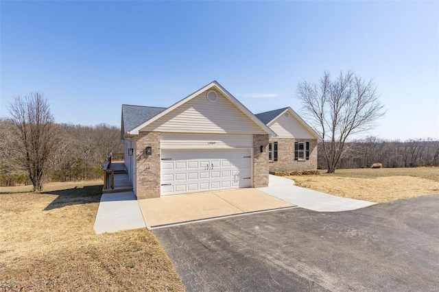 view of front facade with brick siding, an attached garage, and driveway