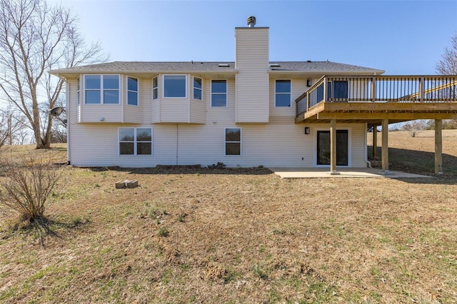 rear view of house with a wooden deck, a lawn, a chimney, and a patio area