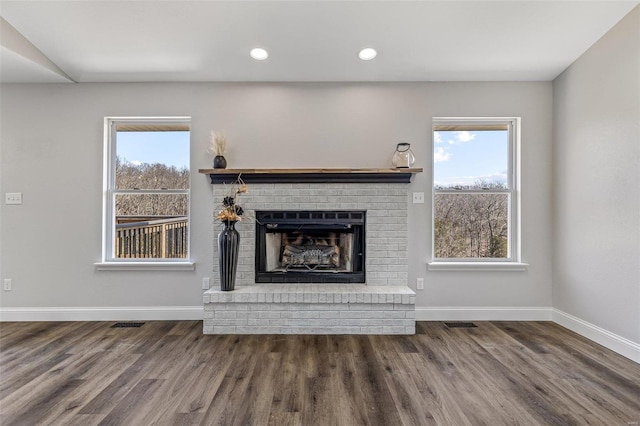 unfurnished living room with a wealth of natural light, baseboards, and a brick fireplace