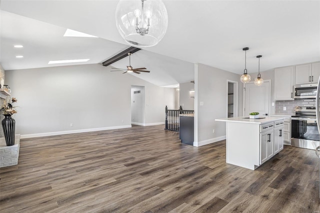 kitchen featuring backsplash, open floor plan, dark wood finished floors, stainless steel appliances, and vaulted ceiling with skylight