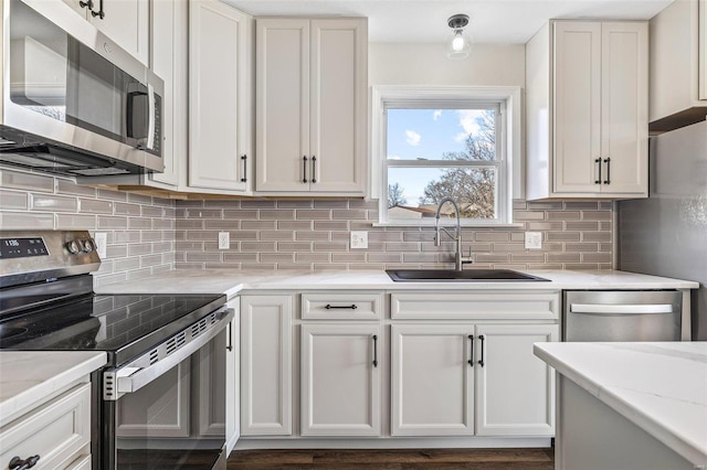 kitchen featuring a sink, tasteful backsplash, white cabinetry, and stainless steel appliances