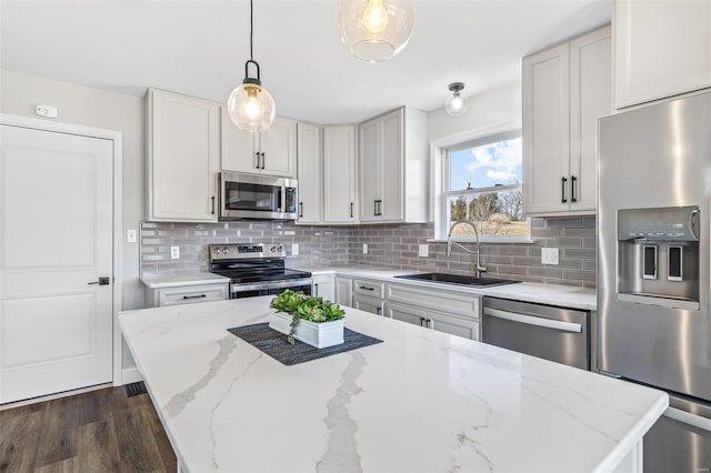 kitchen featuring pendant lighting, a sink, appliances with stainless steel finishes, decorative backsplash, and dark wood-style flooring