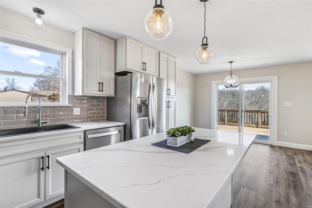 kitchen featuring tasteful backsplash, a center island, dark wood finished floors, appliances with stainless steel finishes, and a sink