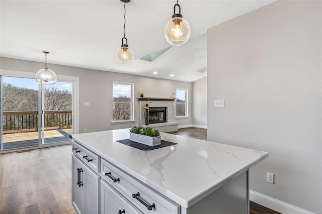 kitchen featuring baseboards, pendant lighting, dark wood finished floors, and a fireplace