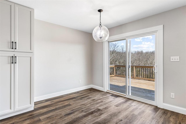 unfurnished dining area with an inviting chandelier, dark wood-style floors, visible vents, and baseboards