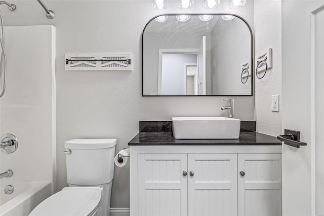 full bathroom with tub / shower combination, toilet, vanity, and a textured wall