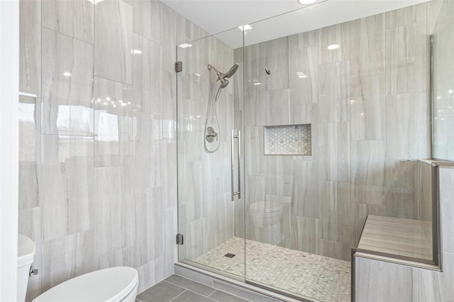 full bathroom featuring tile patterned flooring, a shower stall, toilet, and tile walls