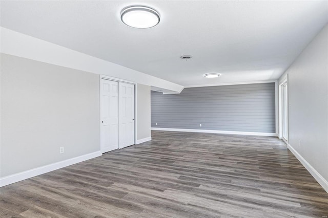 spare room with baseboards and wood finished floors