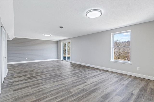 unfurnished room featuring wood finished floors, a healthy amount of sunlight, and baseboards