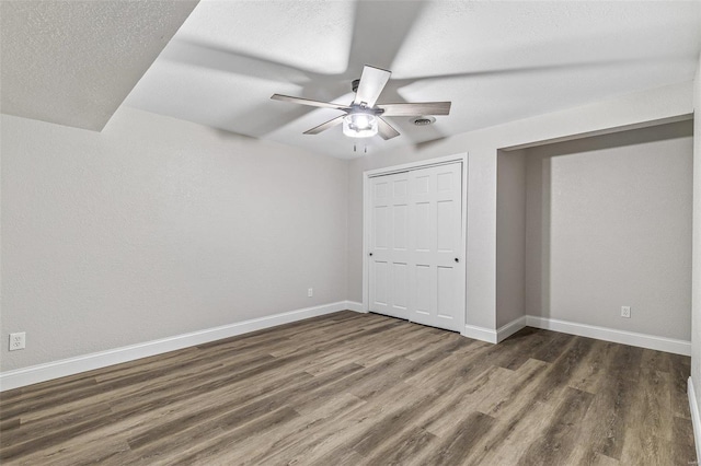 unfurnished bedroom with a ceiling fan, wood finished floors, baseboards, a closet, and a textured ceiling