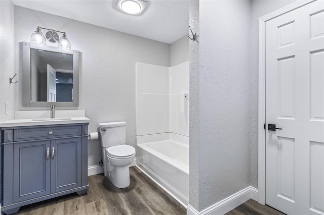 bathroom with vanity, toilet, wood finished floors, and baseboards