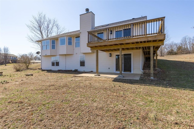 rear view of property with a chimney, a patio area, a lawn, and a wooden deck