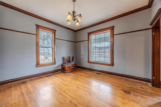 spare room featuring visible vents, baseboards, ornamental molding, hardwood / wood-style flooring, and a notable chandelier