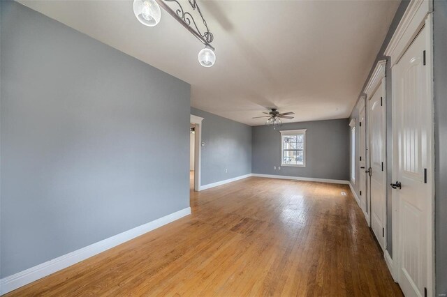 unfurnished room featuring light wood-style flooring, a ceiling fan, and baseboards