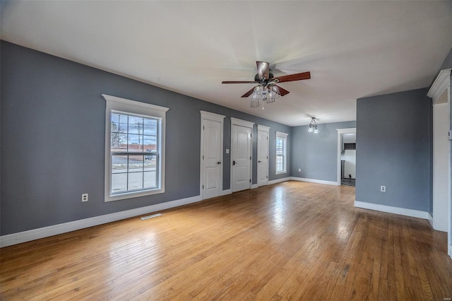 interior space with visible vents, ceiling fan with notable chandelier, baseboards, and hardwood / wood-style flooring