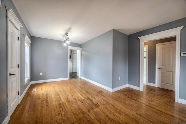 spare room with baseboards and wood finished floors