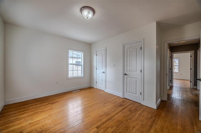 unfurnished bedroom with multiple closets, baseboards, and wood-type flooring