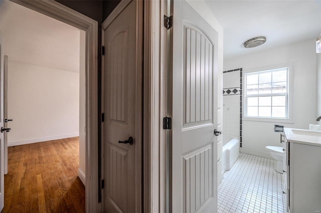 bathroom featuring tile patterned floors, toilet, shower / washtub combination, baseboards, and vanity