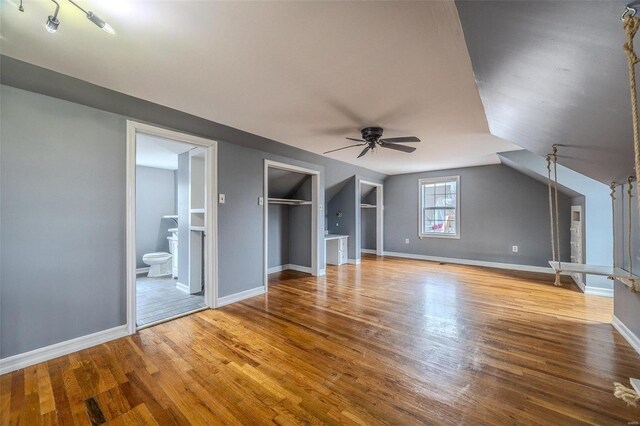 interior space with ceiling fan, baseboards, wood finished floors, and vaulted ceiling