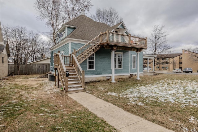 back of property featuring stairway, fence, roof with shingles, and a wooden deck