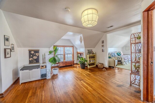 additional living space with lofted ceiling, visible vents, baseboards, and wood-type flooring