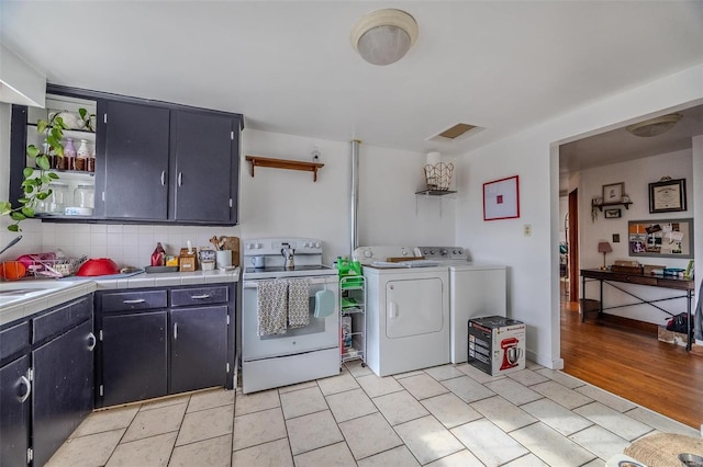 kitchen featuring open shelves, tile counters, electric stove, and washing machine and dryer