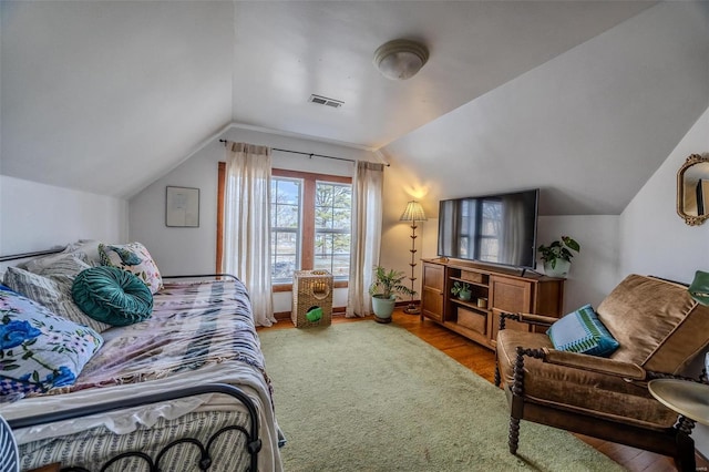 bedroom with visible vents, baseboards, lofted ceiling, and wood finished floors