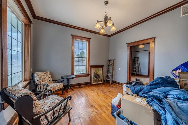 living area featuring visible vents, baseboards, light wood-style flooring, ornamental molding, and a chandelier