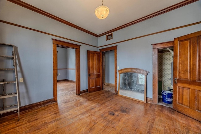 unfurnished bedroom with visible vents, baseboards, crown molding, and light wood-style floors