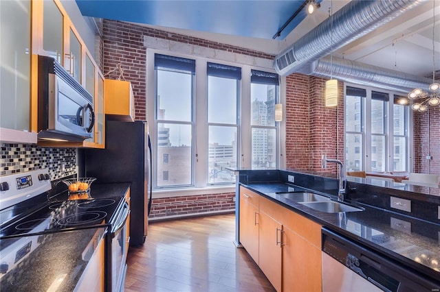 kitchen featuring a sink, stainless steel appliances, a healthy amount of sunlight, and brick wall