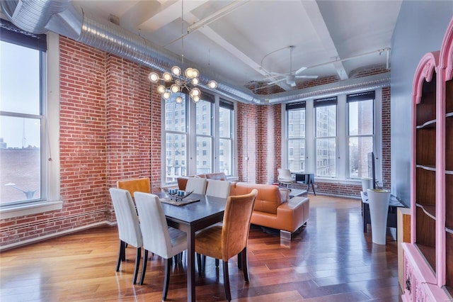 dining room featuring a chandelier, brick wall, and wood finished floors