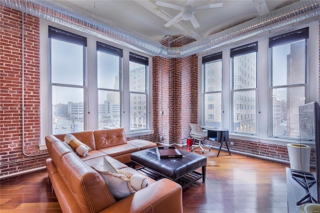 living room with ceiling fan, wood finished floors, brick wall, and a view of city