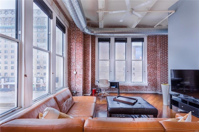 living room with wood finished floors and brick wall