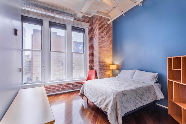 bedroom with wood-type flooring and brick wall