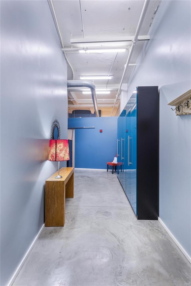 hallway with baseboards and concrete flooring