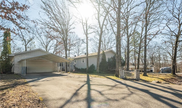 view of front of home with brick siding, driveway, and a carport