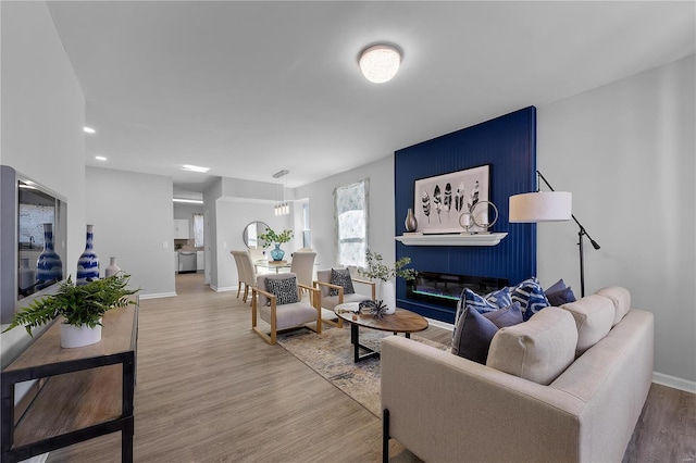 living area featuring a fireplace, recessed lighting, wood finished floors, and baseboards