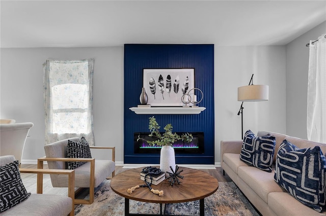 living room featuring baseboards, wood finished floors, and a glass covered fireplace