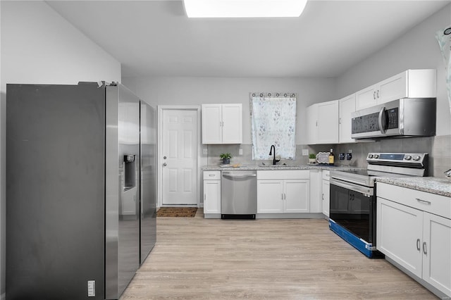 kitchen featuring a sink, light wood finished floors, white cabinetry, and stainless steel appliances