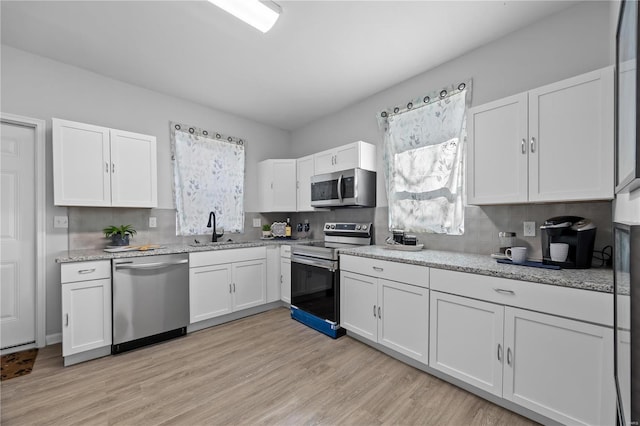 kitchen with white cabinets, stainless steel appliances, a healthy amount of sunlight, and a sink