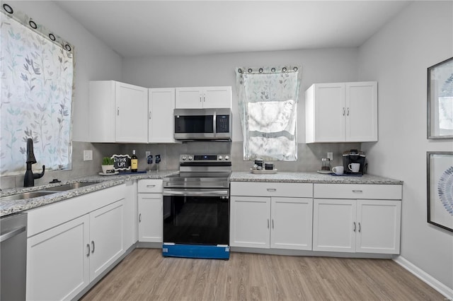 kitchen featuring white cabinetry, light wood-style flooring, appliances with stainless steel finishes, and a sink