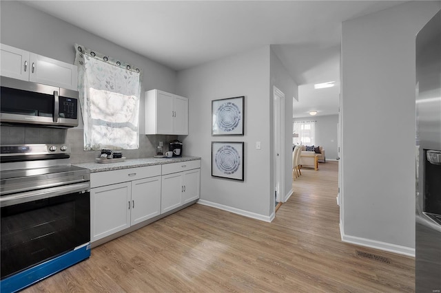 kitchen with light wood-type flooring, stainless steel appliances, visible vents, and white cabinetry