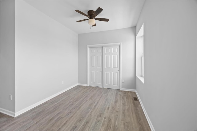 unfurnished bedroom with visible vents, baseboards, wood finished floors, a closet, and a ceiling fan