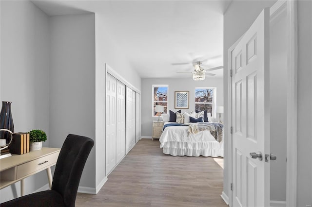 bedroom with a ceiling fan, wood finished floors, baseboards, and a closet