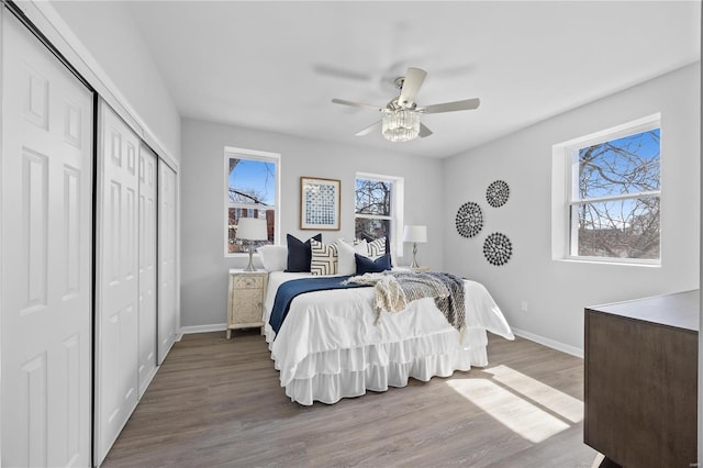 bedroom with a closet, multiple windows, baseboards, and wood finished floors