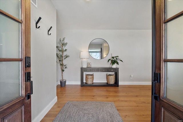 foyer entrance with visible vents, light wood-style floors, and baseboards